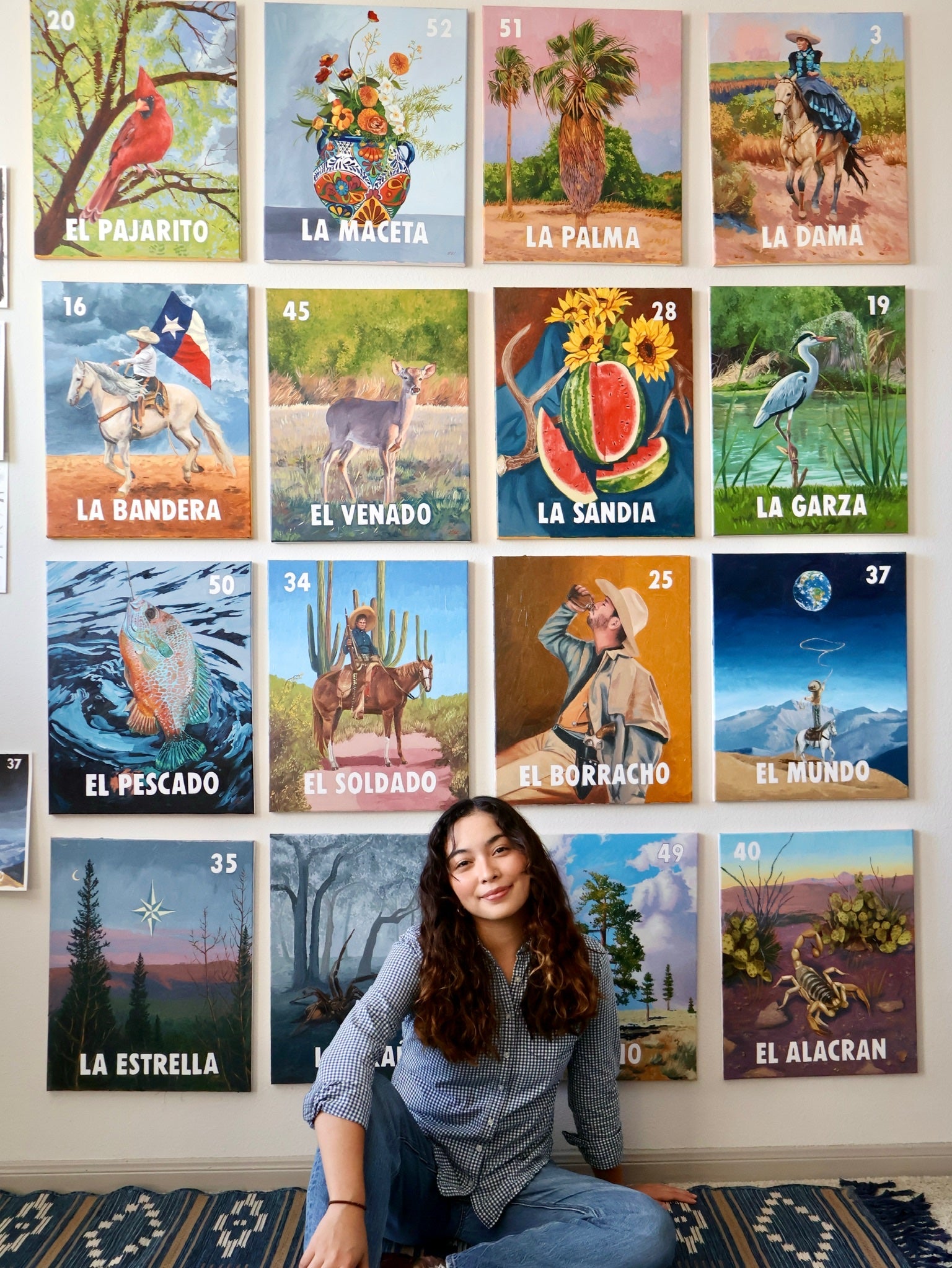 Leslie De Leon posing in front of a wall with 16 colorful paintings featuring various scenes and objects.