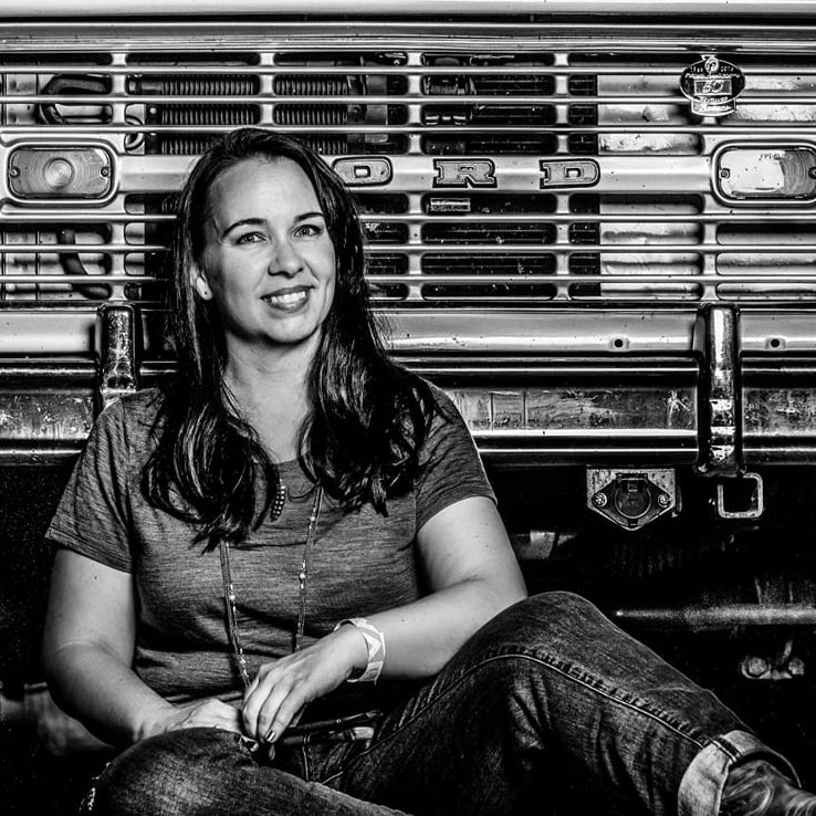 Woman sitting in front of a vintage Ford Bronco vehicle